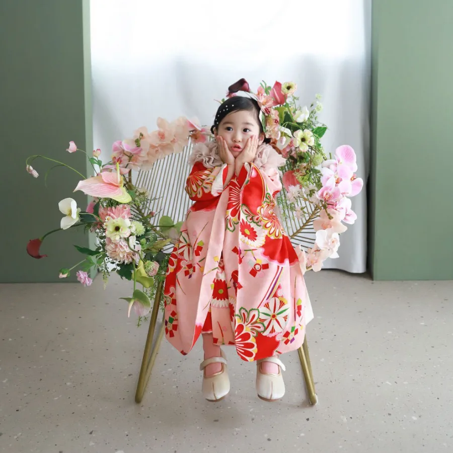 花に囲まれた椅子に座る着物姿の女の子
